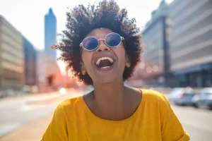 Smiling woman laughing outdoors representing the mental health benefits of laughter