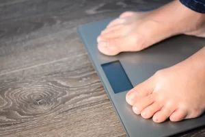 Person standing on weighing scales reflecting concerns about weight and health